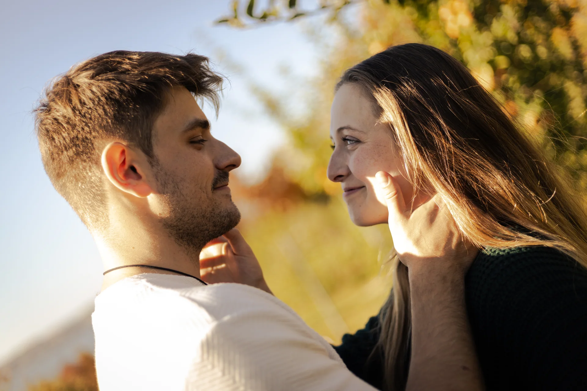 Un couple se regarde en souriant dans la lumière du soleil.